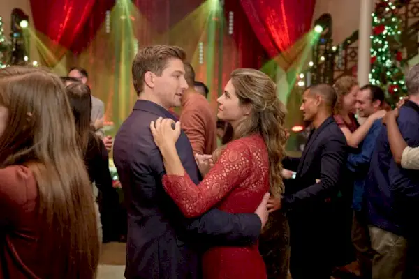 Jonathan Bennett, Hunter King et Craig Geoghan souriant devant les décorations de Noël.