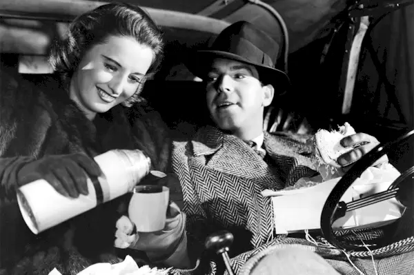 Barbara Stanwyck verse du café à Fred MacMurray en train de manger un sandwich