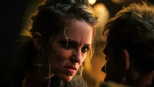 A woman with unkempt hair leans into someone