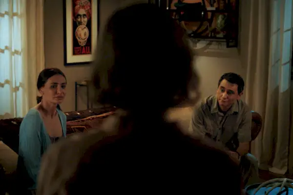 Une femme debout regardant un homme et une femme assise sur un canapé