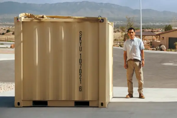 Un homme debout à côté d’une grande caisse jaune