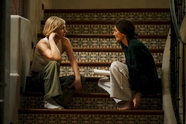 Dos mujeres sentadas en el penúltimo escalón de una escalera.